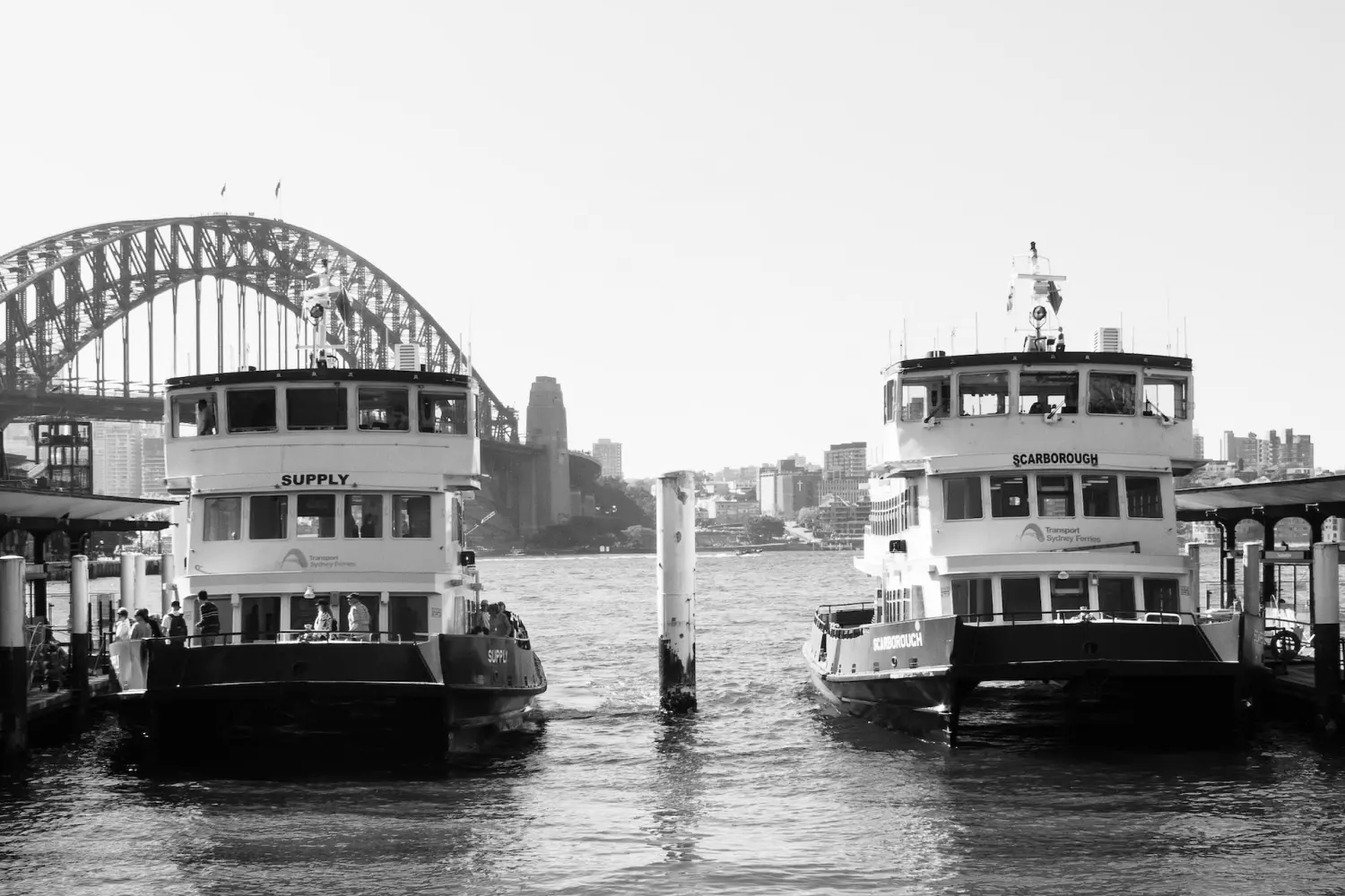 Black and white image of two old river boats docking at the port.