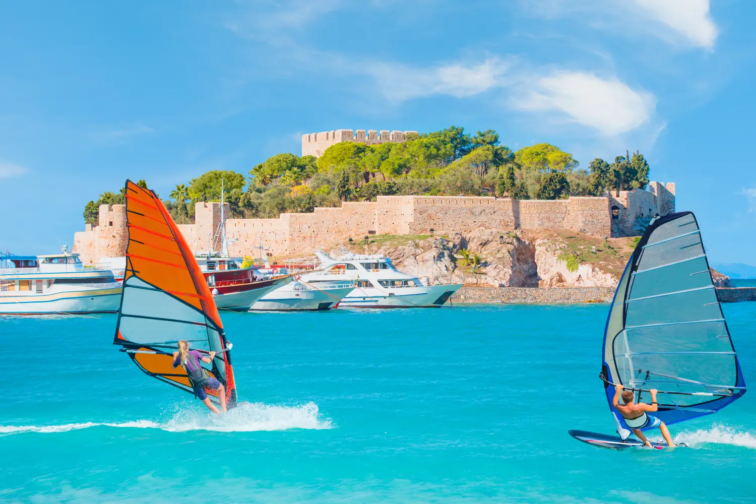 Ferry to Kusadasi - Windsurfer surfing the wind on waves in Kusadasi. Pigeon Island with a Pirate castle Kusadasi harbor, Aegean coast of Turkey.