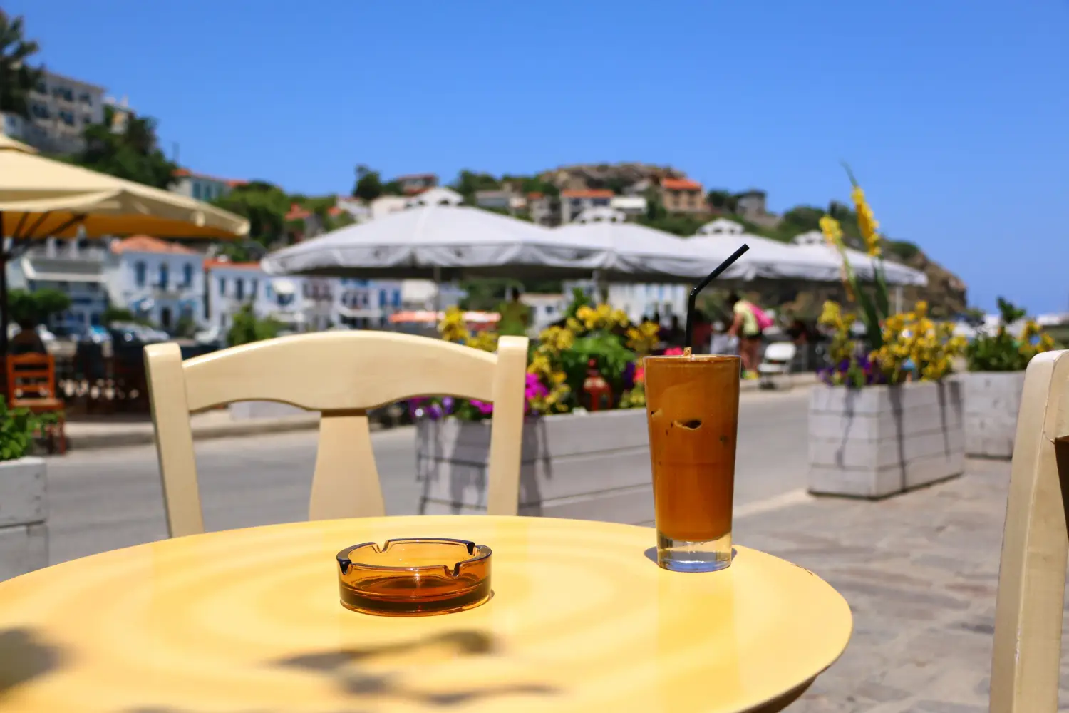 Ferry to Evdilos (Ikaria) - Greek frappe coffee and ashtray on a table at the port of Evdilos, Ikaria, North Aegean islands.