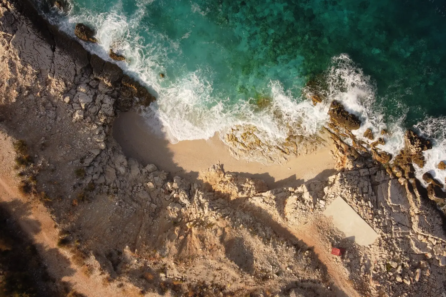 Ferry to Himare - Aerial view of the sea waves washing out on a sandy beach.