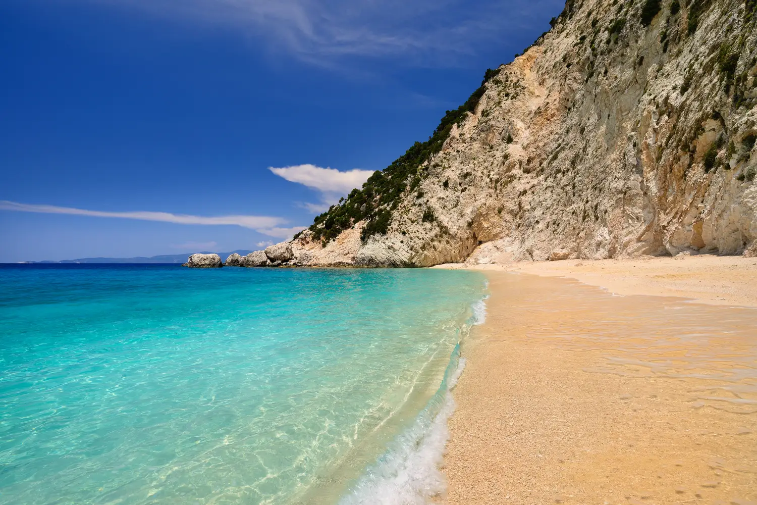 Ferry to Ithaca - Sandy beach with rocky mountains and clear blue sea along the northern coast of the Greek island of Ithaca in the Ionian Sea.