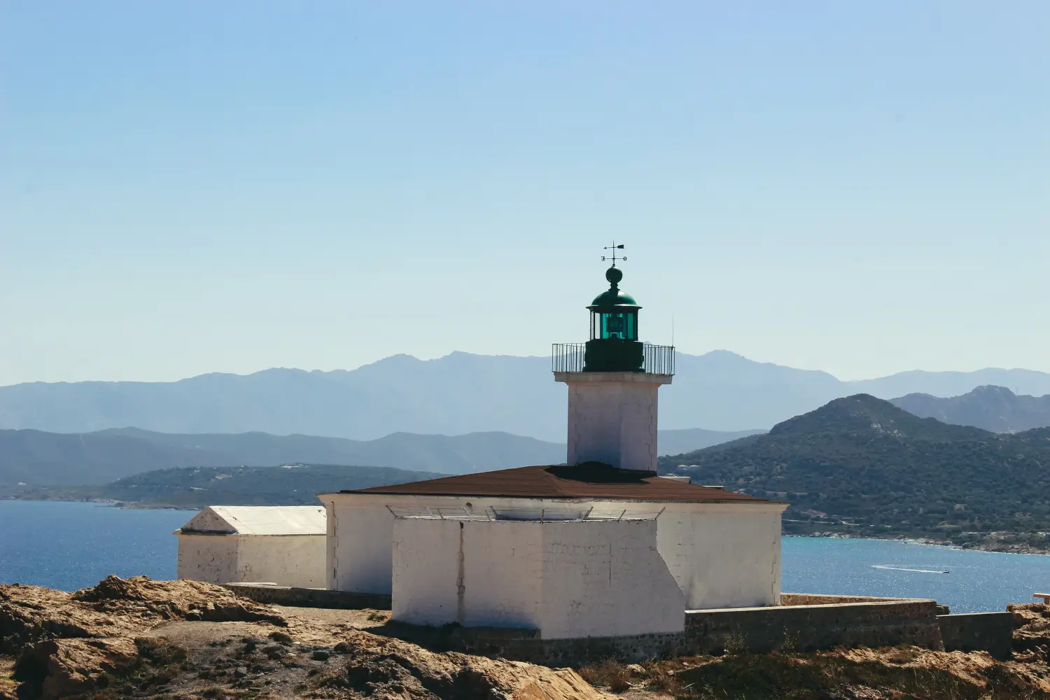Ferry to Ile Rousse - A light house at the cliff's edge overlooks the sea and the golf.