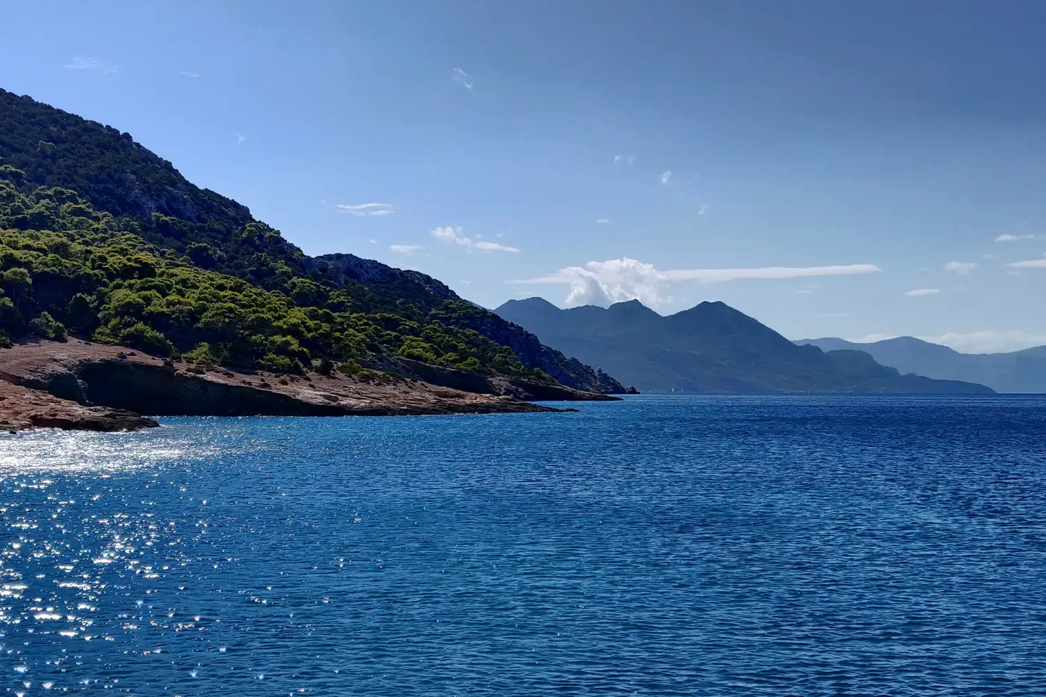 Ferry to Myli (Agistri) - Beautiful blue sea and lush vegetation on a cliff.