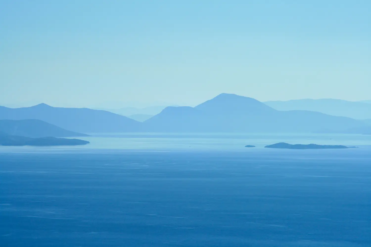 Ferry to Agios Konstantinos - Image of a blueish horizon with foggy mountain ranges in the background.