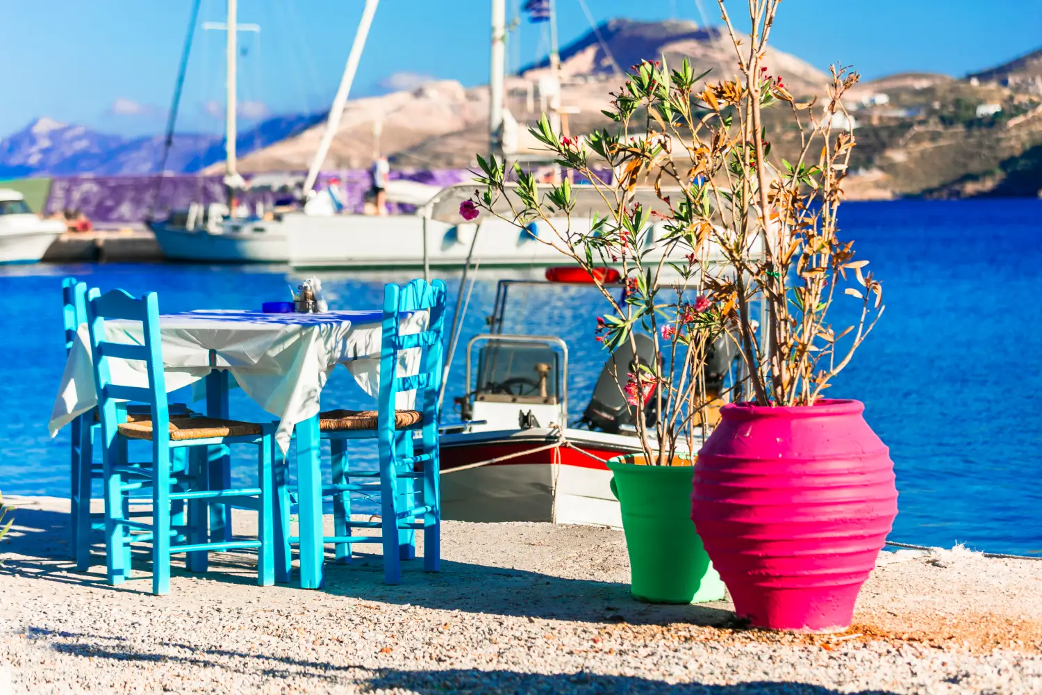 Ferry to Agia Marina Leros - Picturesque scenery consisting of clay cubes and a taverna table with chairs in front of a small port.