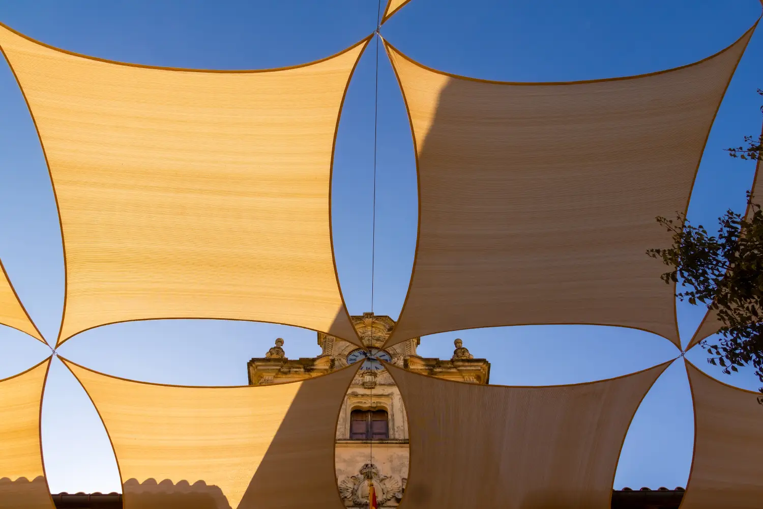 Ferry to Alcudia - Looking through sail shaped sunshades at the Ayuntamiento clock tower, old town Alcudia, Mallorca, Spain.