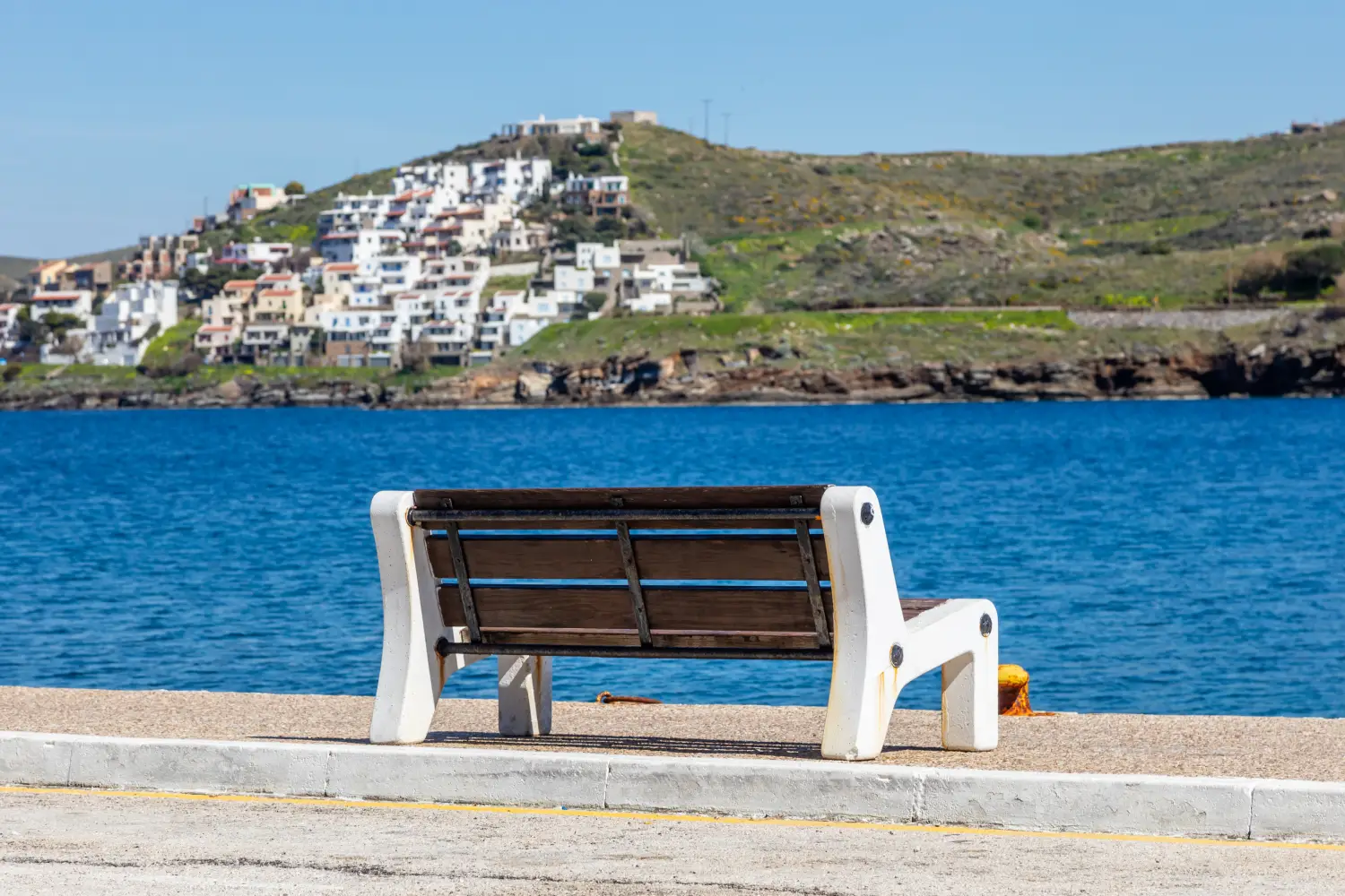 Ferry to Kea - Empty bench in Tzia port Korissia on blue sea and sky background.