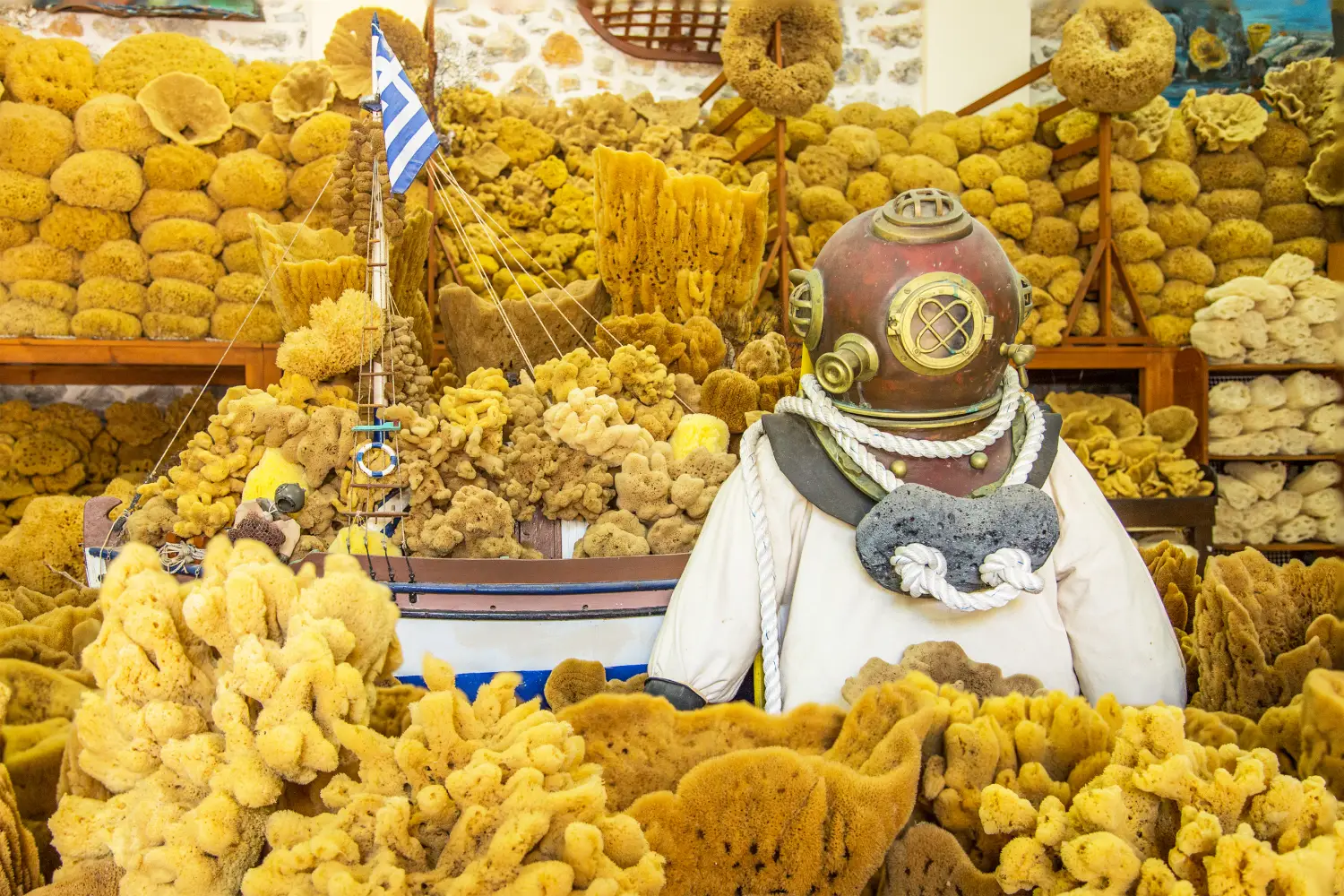 Ferry to Kalymnos - A vintage diving suit with helmet with natural sponges in the background, Greece.